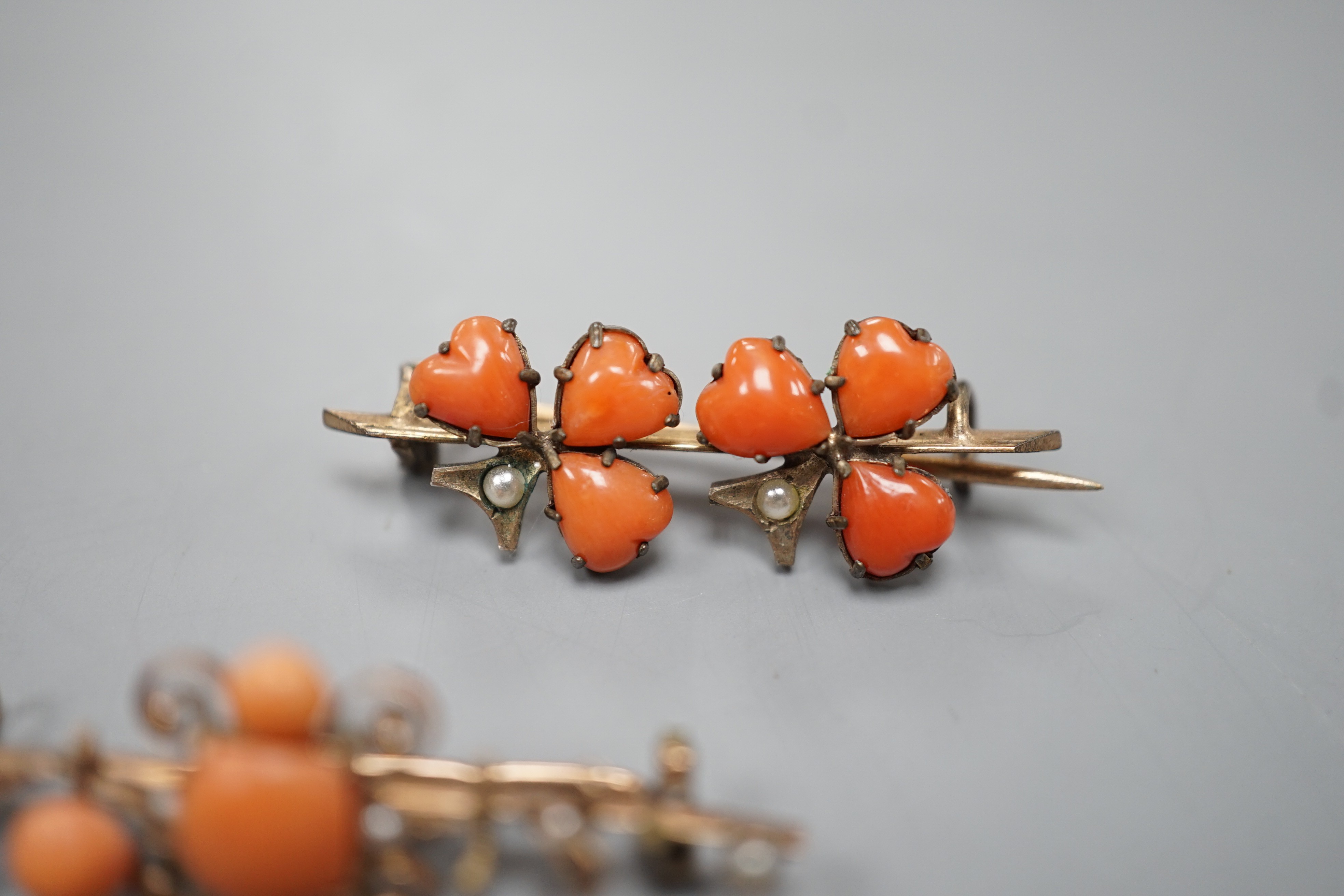 Two early 20th century yellow metal seed pearl and coral set brooches, one stamped 333 (8ct), largest 38mm, gross weight 3.8 grams.